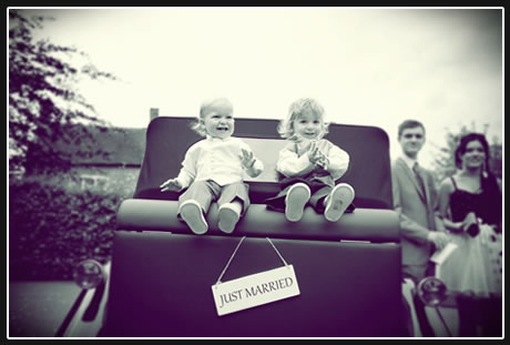 two young children sat on the back of the beauford classic wedding car